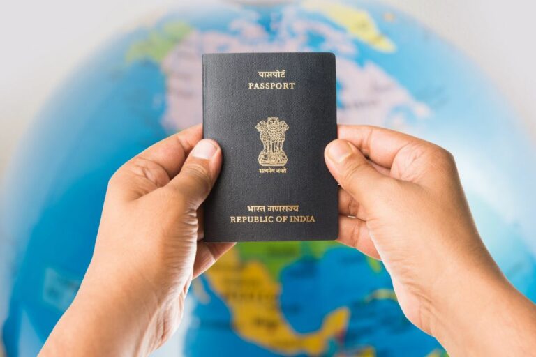 Hands holding an Indian passport in front of a globe